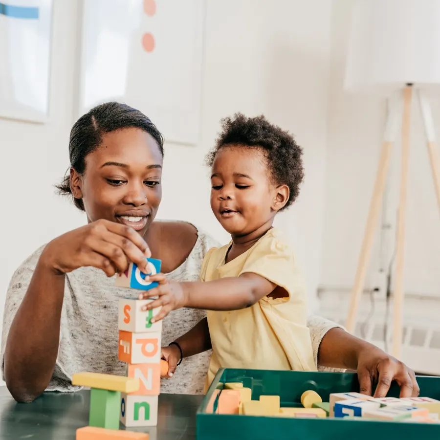 A caregiver feeding a baby, part of early childhood support