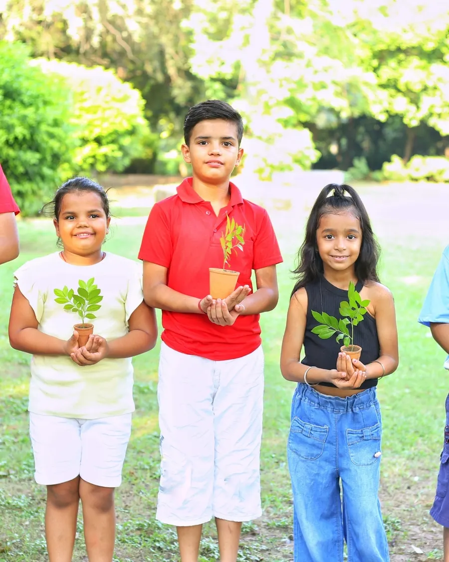 Children smiling and holding plants they grew at an Unbreakable Kids community garden